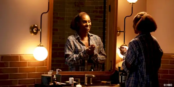 Issa Rae as Issa Dee standing in front of a dimly lit mirror smiling at herself in Insecure.