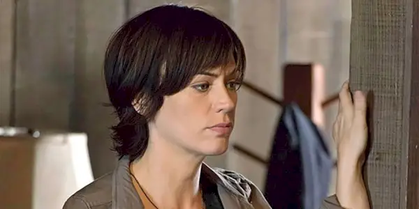 Tara from Sons of Anarchy with short hair, hand on the wall looking outside of a room.