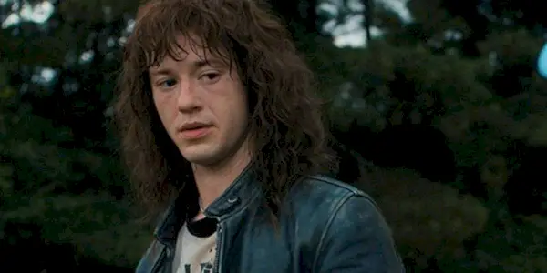 Eddie Munson from Stranger Things in the first, looking down at Chrissy, looking serious.